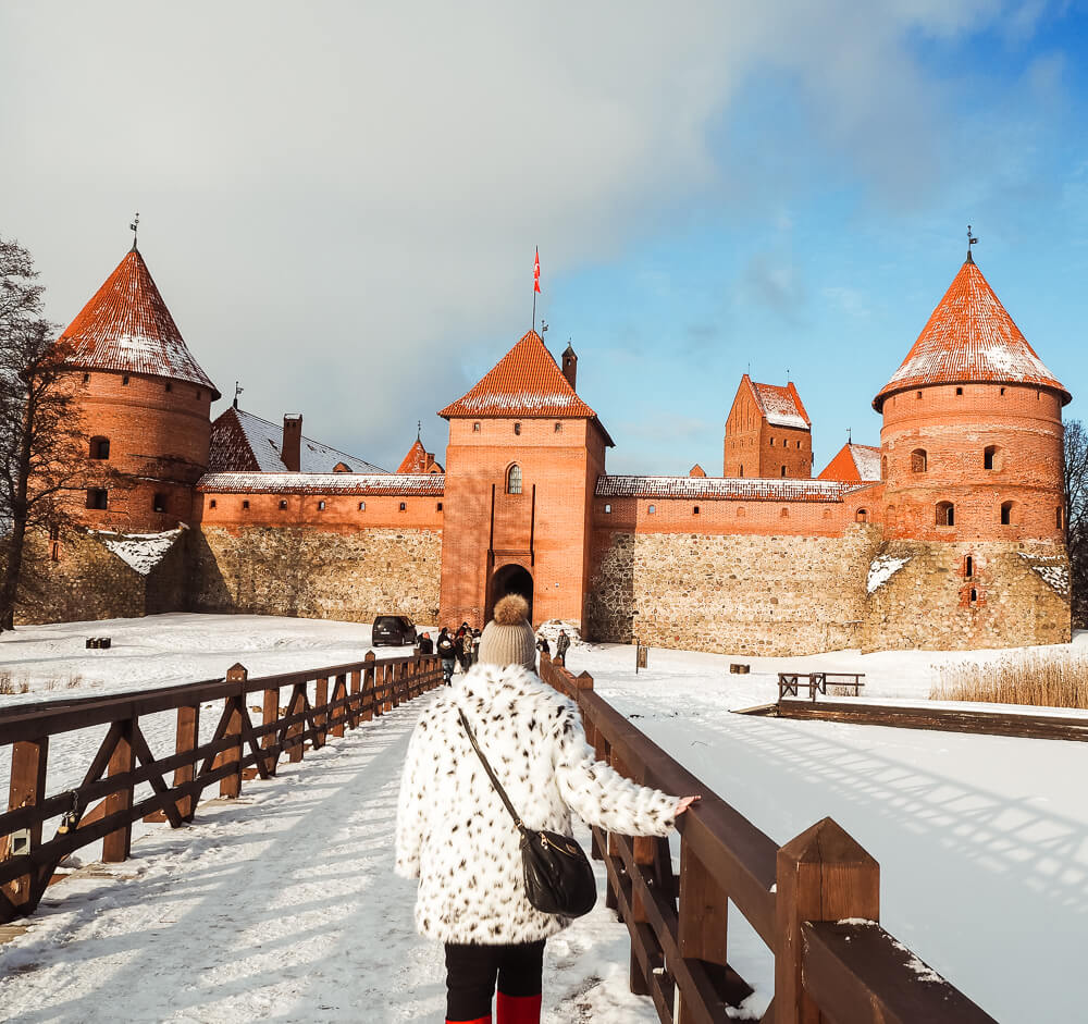 Woman walking across a wooden bridge at Trakai Castle one of the best day trips from Vilnius