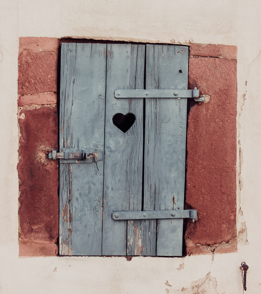 A blue wooden door with a heart shape cut out from it.