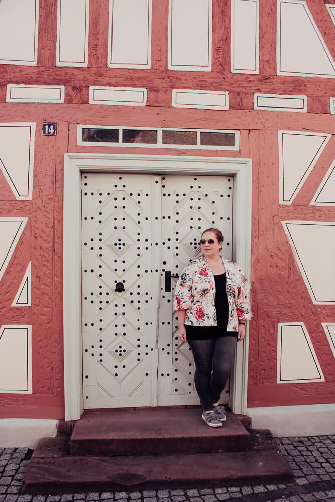 Woman wearing a floral top and jeans in the fairytale village of Michelstadt.