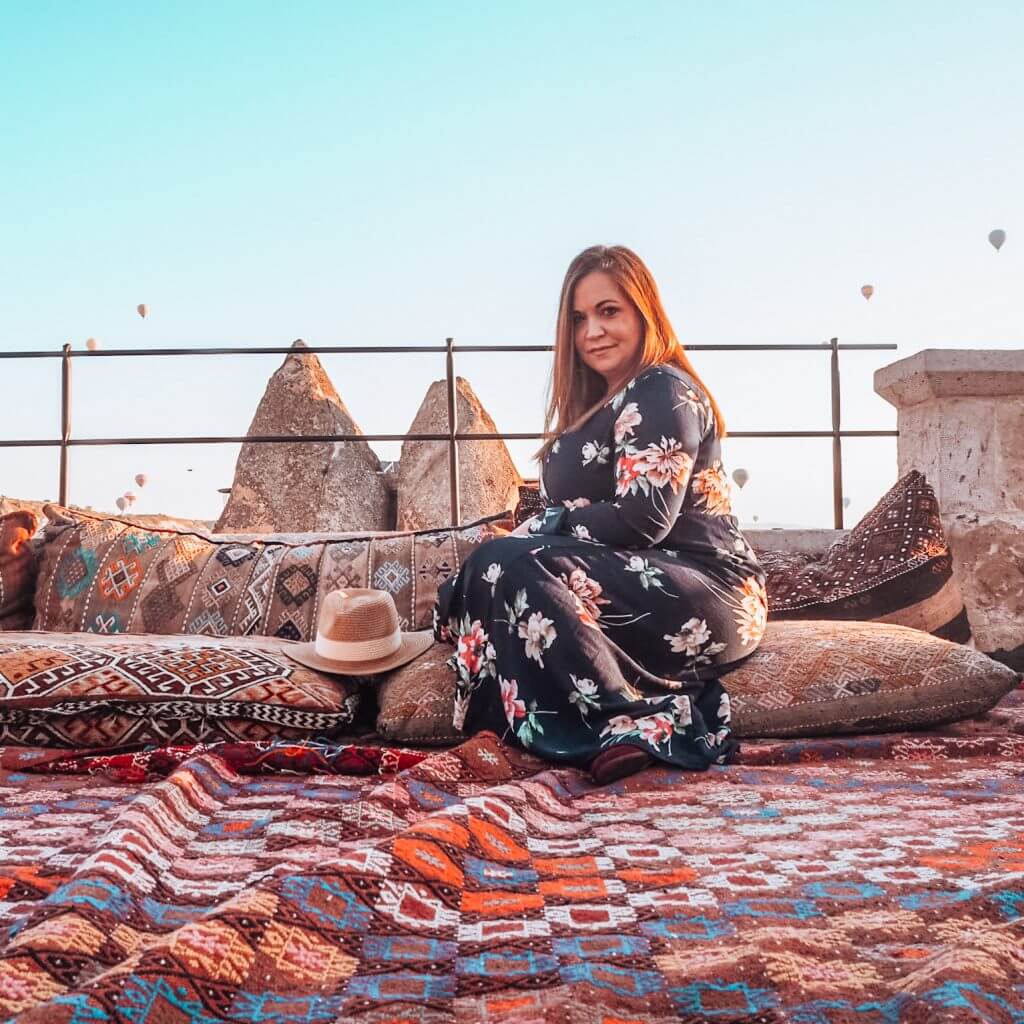 Woman watching hot air balloons at the teracce of the Sultan Cave Suite Hotel Goreme Cappadocia, Turkey.