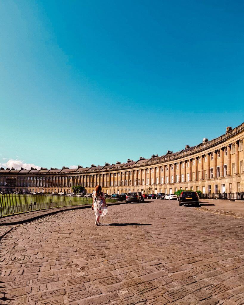 Women in a summer dress walking towards the crescent shaped homes of Bath UK