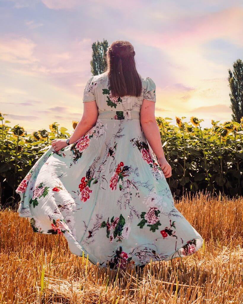 Woman in a long blue dress in a field of sunflowers