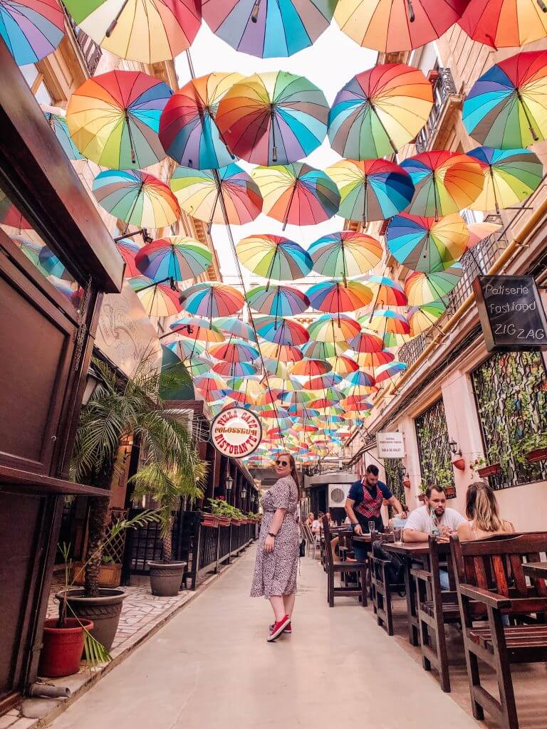 Woman walking under a beautiful Umbrella Sky in Bucharest Old Town.