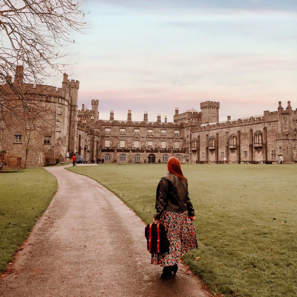 Woman wearing a floral dress and black jacket exploring the grounds of Kilkenny castle