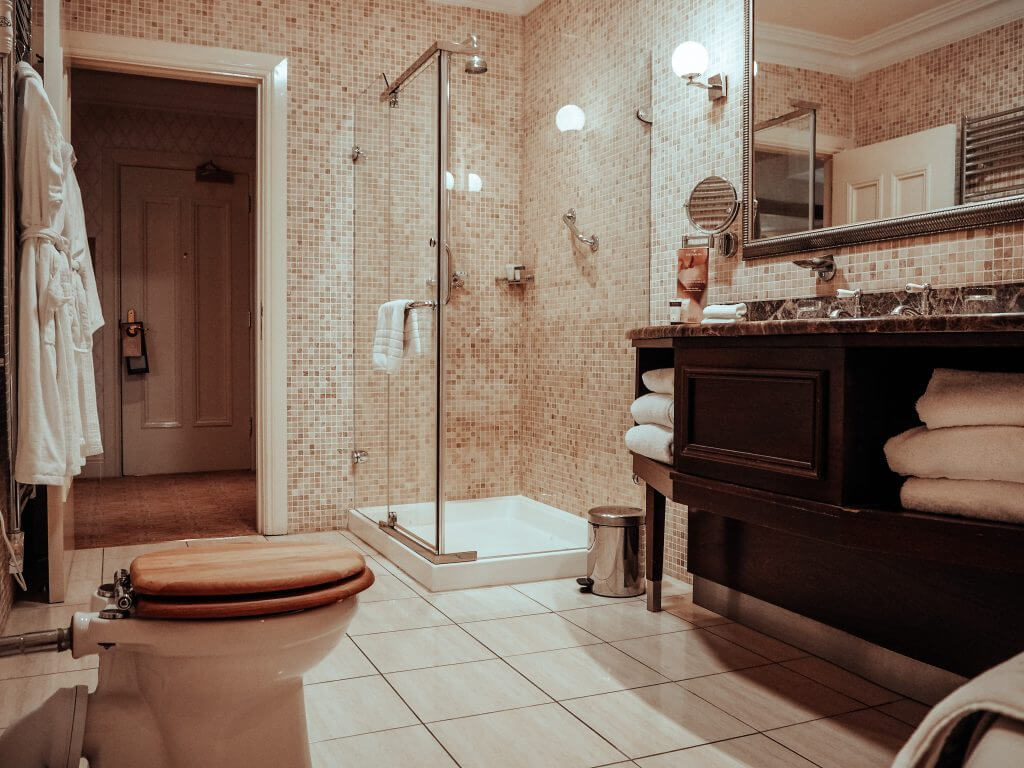 Bathroom with dark wooden counters and beige mosaic tiles at the Dovecote suite in Lough Erne Resort
