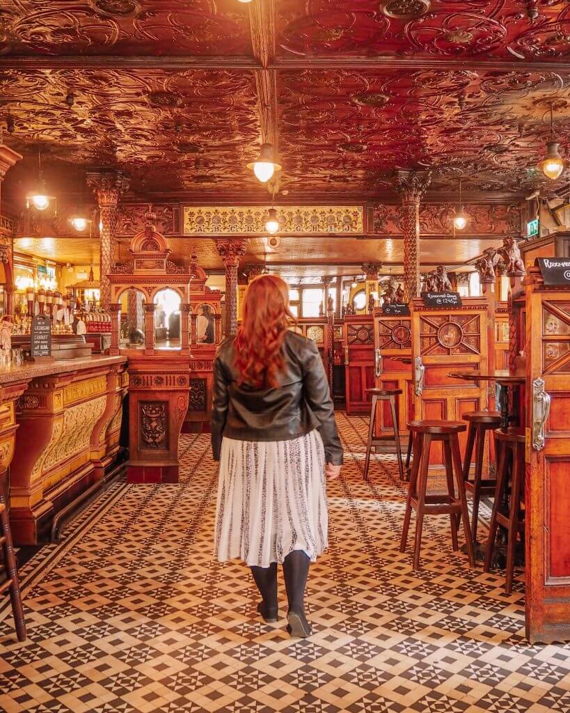 Woman in a white dress walking into the Crown Bar in Belfast