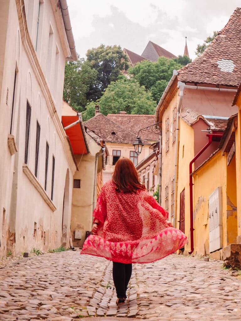 Woman walking through the colourful streets of Sighisoara