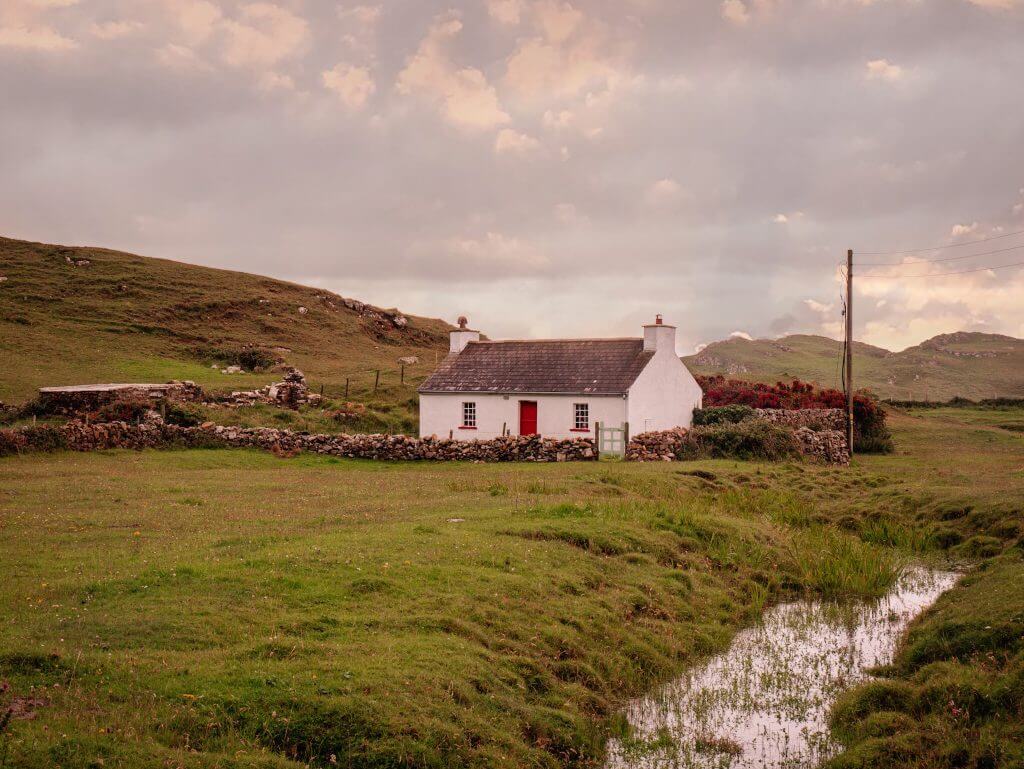 Cottage with a red door at the entrance to Murder Hole Beach in County Donegal