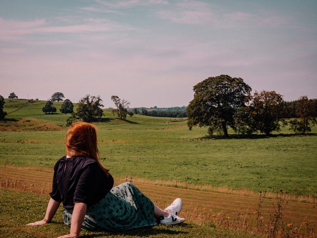 Woman sitting on the grass and enjoying the views at Loughcrew Estateand gardens a wonderful thing to do in County Meath Ireland