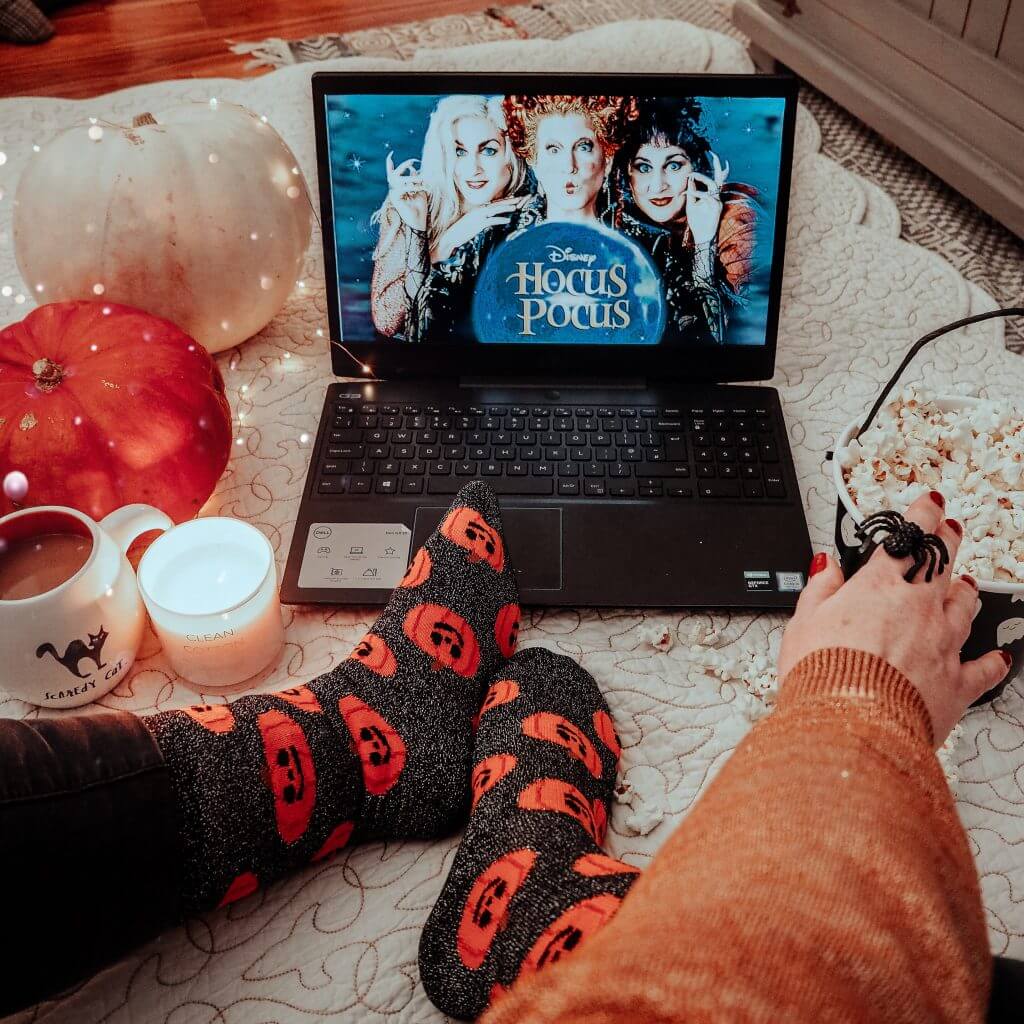 Woman taking an Instagram photo while eating popcorn and watching Hocus Pocus at Halloween