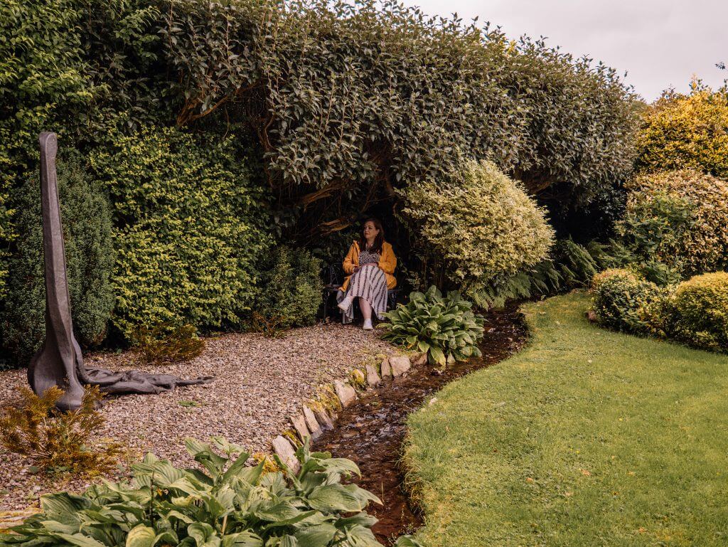 Woman in a yellow raincoat in a seating area at Shekina Sculpture Garden