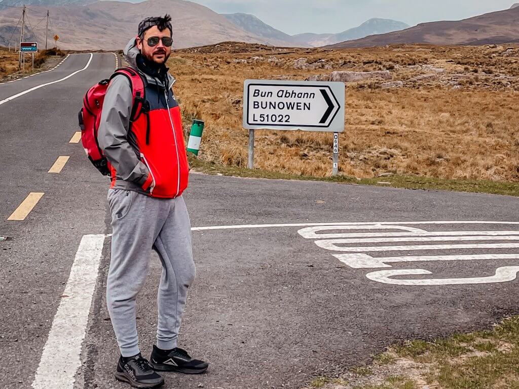 Man wearing a grey tracksuit and red rain jacket at the start of the Killary Harbour Coastal Walk in Connemara Ireland