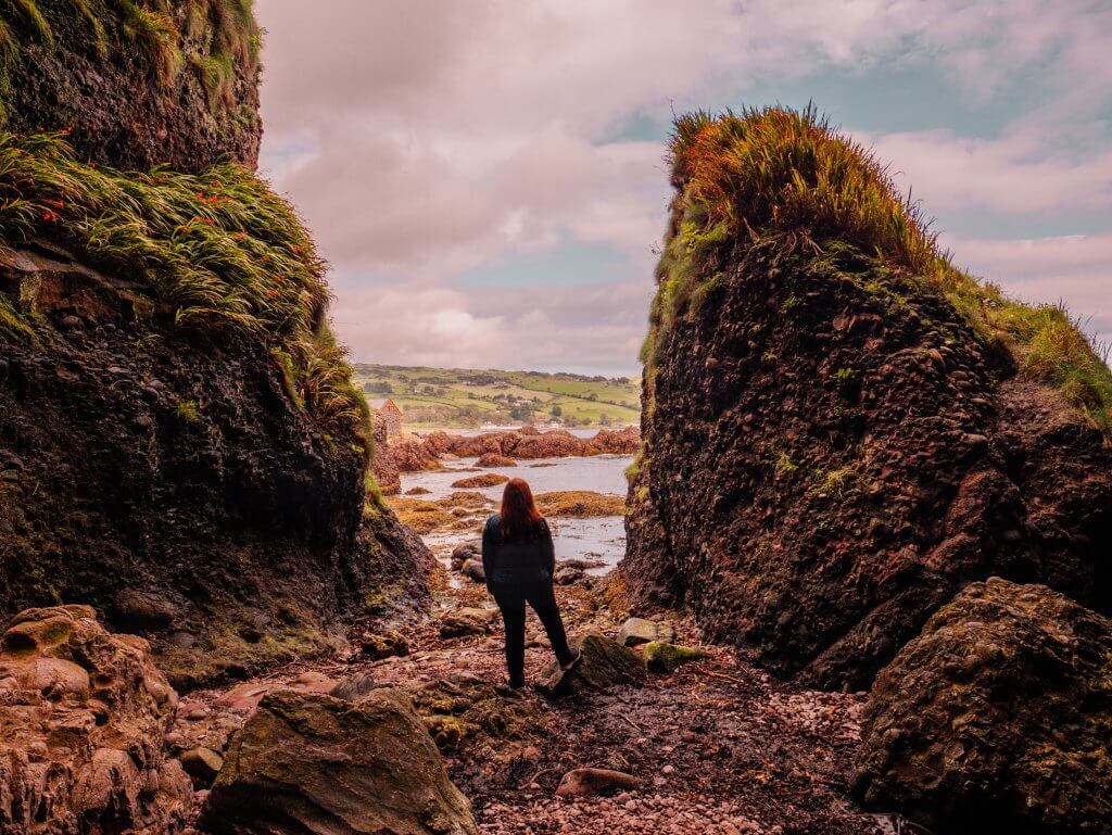 Woman looking at the Antrim coastline at Cushendun caves a games of thrones filming location in Northern Ireland