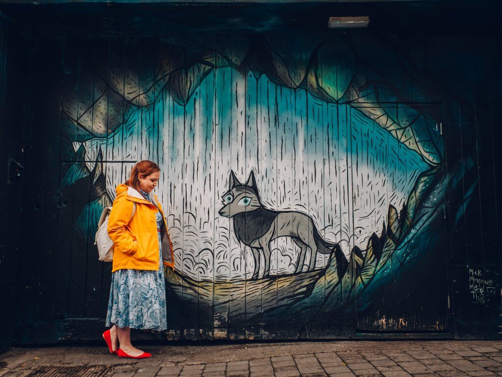 Woman in a yellow raincaot looking at some street rt in Kilkenny Ireland