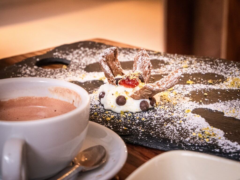 Cup of hot chocolate beside a plate of cannoli
