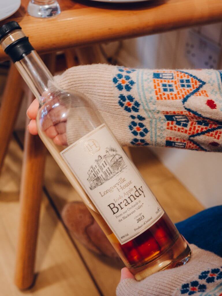 Woman holding a bottle of Longueville House whiskey on a Galway Food Tour
