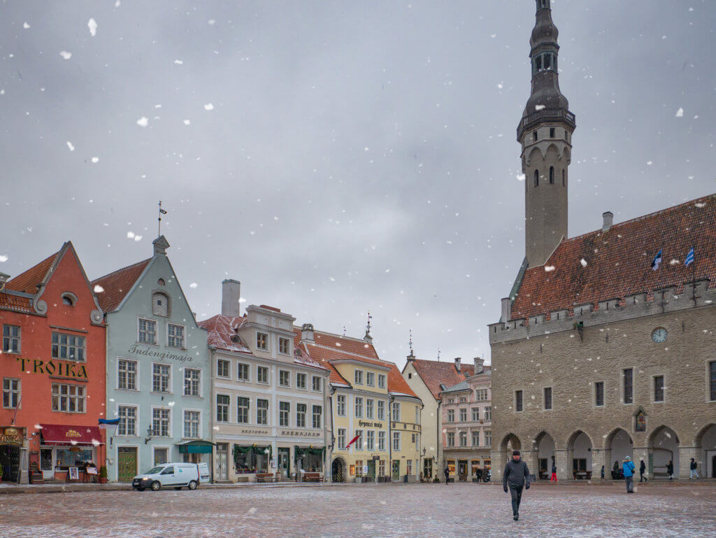 People walking in the snow in Tallinn's Town Hall Square in Old Town Tallinn in winter.