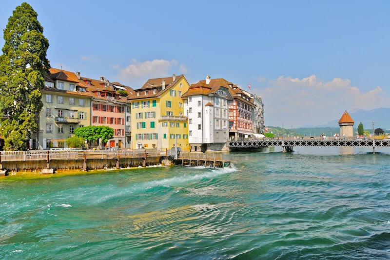 Colourful buildings in Lucerne Old Town at the edge of the River Reuss and view of the famous Chapel Bridge in the background