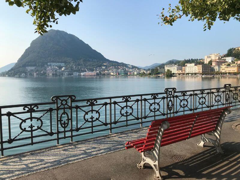 Red bench on the lakeshore of Lake Lugano in Ticino Switzerland.