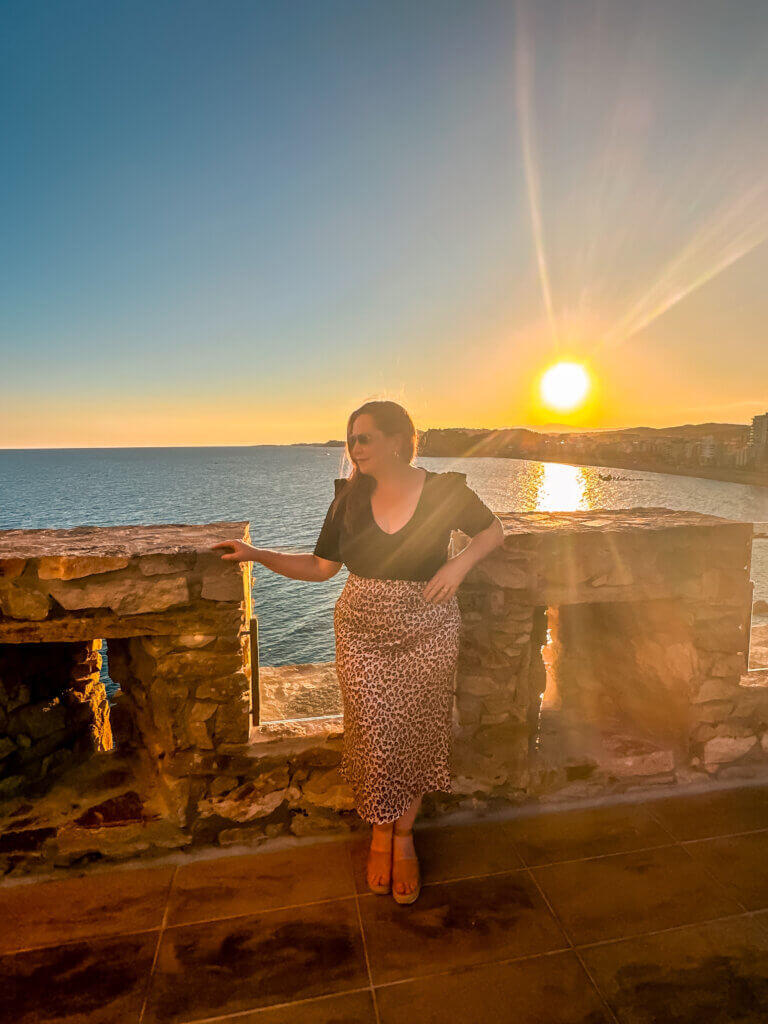 Nicola Lavin, Irish travel blogger from Our Unique Stays, stands at Lloret Castle at sunset