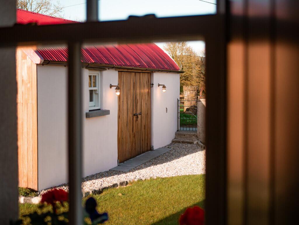 Window framing a red roof barn at Meadow View Farmhouse in Tipperary.