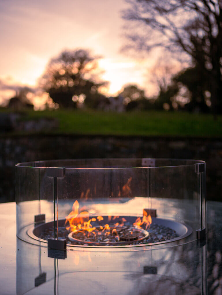 Fire pit at Meadow View Farmhouse at sunset while cows walk in the background.