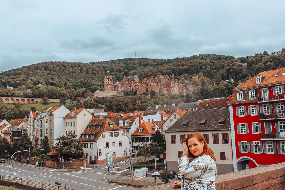 Woman standing on the Alte BrΓΌcke in Heidelberg, Germany the perfect way to spend 1 day in Heidelberg, Germany