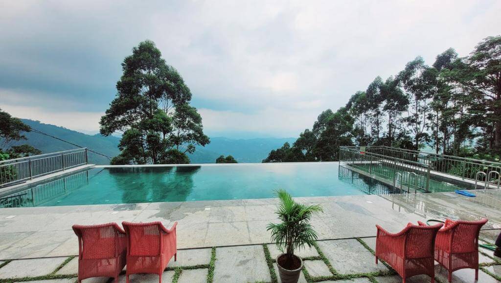 Infinity pool surrounded by lush greenery at a Munnar luxury hotel.