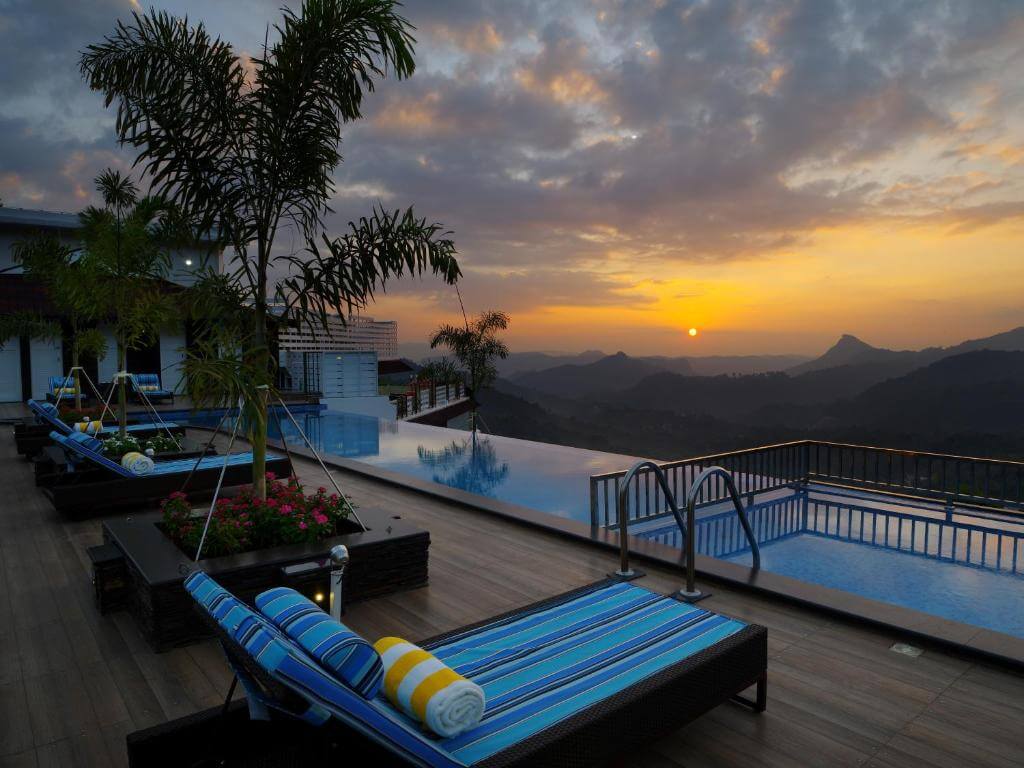 Luxurious infinity pool overlooking the misty mountains of Munnar at sunset.