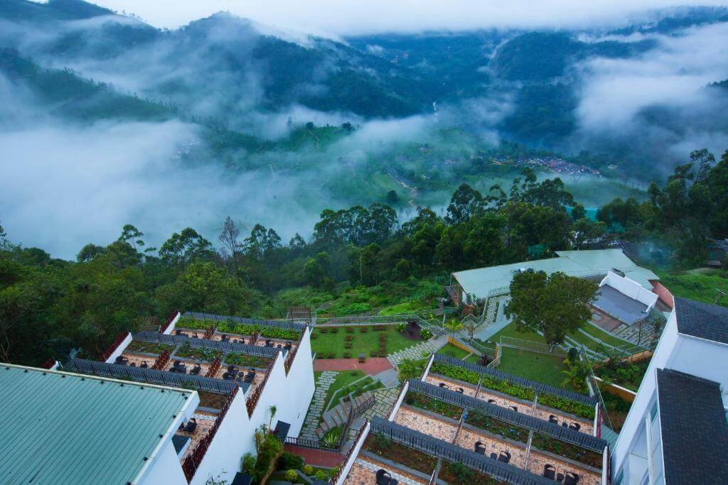 Aerial view of a 5-star hotel nestled in the lush green hills of Munnar.