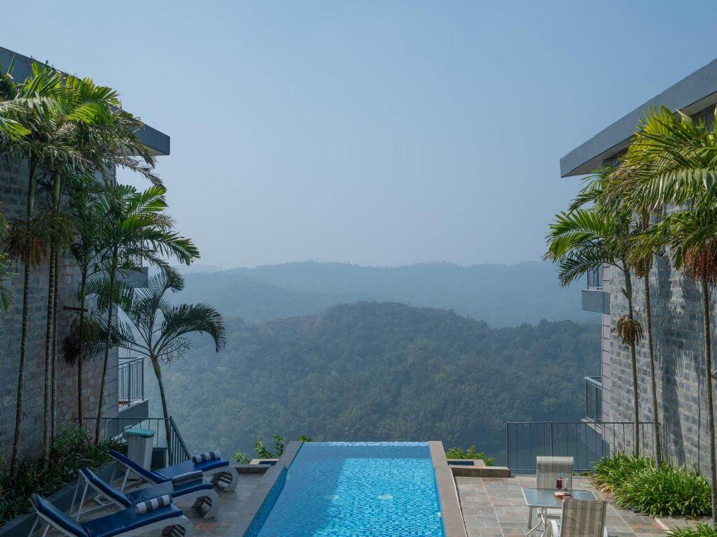 Outdoor pool with nature views at a 5-star hotel in Munnar.