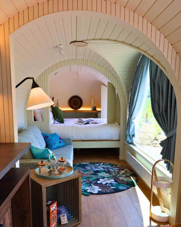 Plush king-size bed with crisp white linens and soft throws inside a luxury cabin in Ireland at Ballygarry Estate.