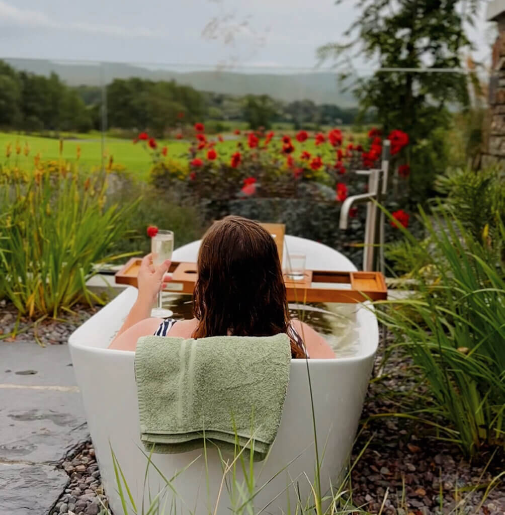 Woman relaxing in a VOYA seaweed bath at Nádúr Spa during a stay in a luxury cabin in Ireland.