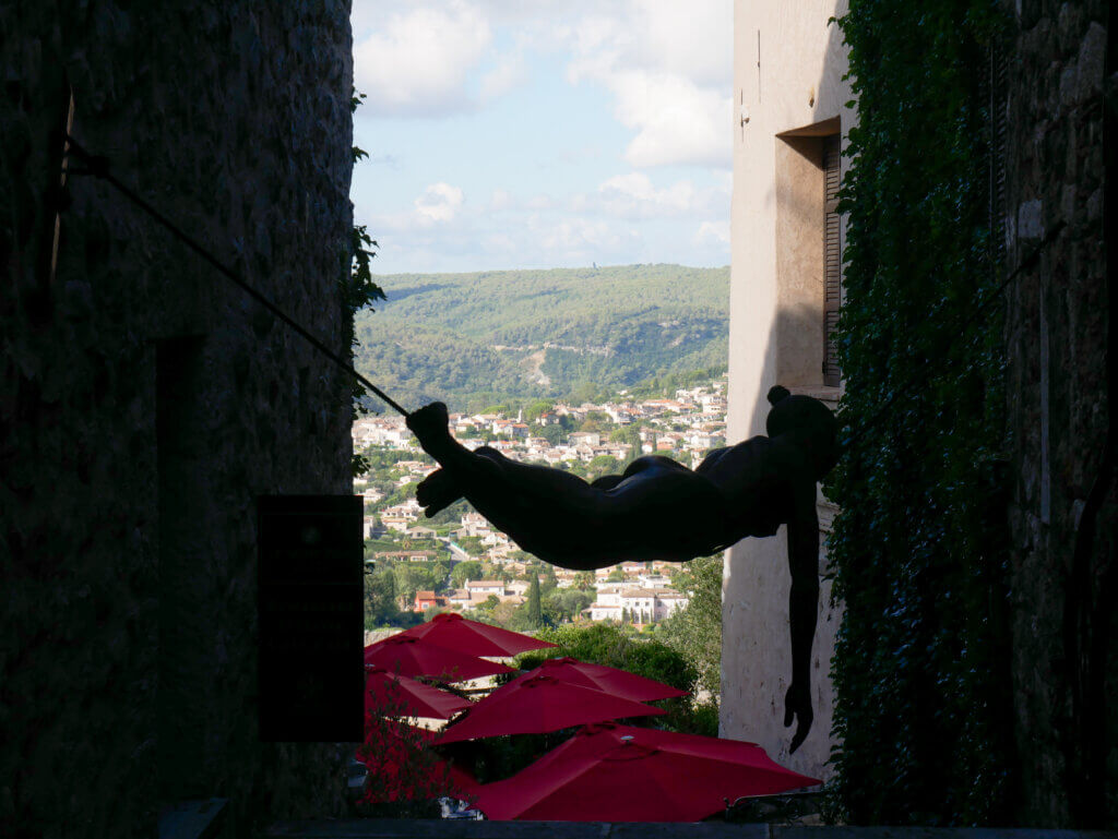 Art sculpture of a woman hanging over the streets of Saint Paul de Vence.