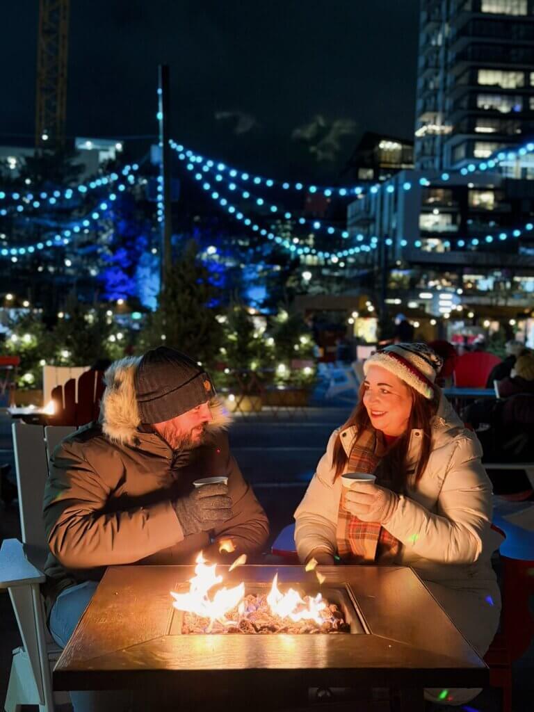 Couple enjoying hot apple cider around a fire pit at the Evergreen festival in Halifax, Nova Scotia, Canada.