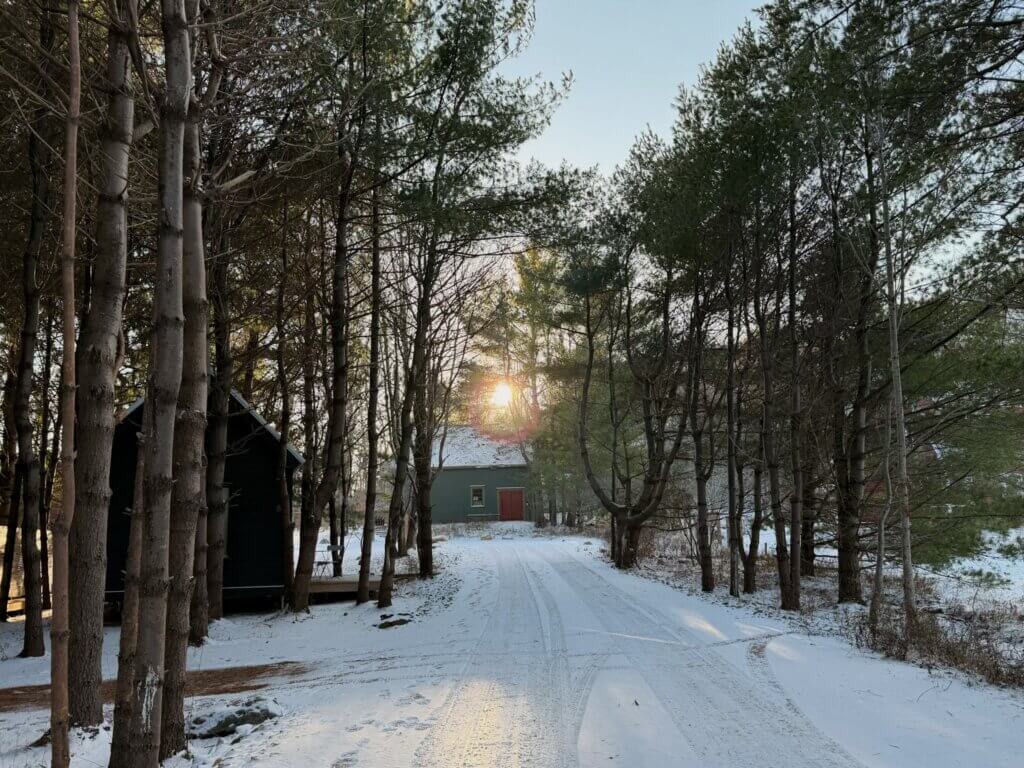 Black Forest Cabins in Mahone Bay, Nova Scotia, at sunset. There is snow on the ground.