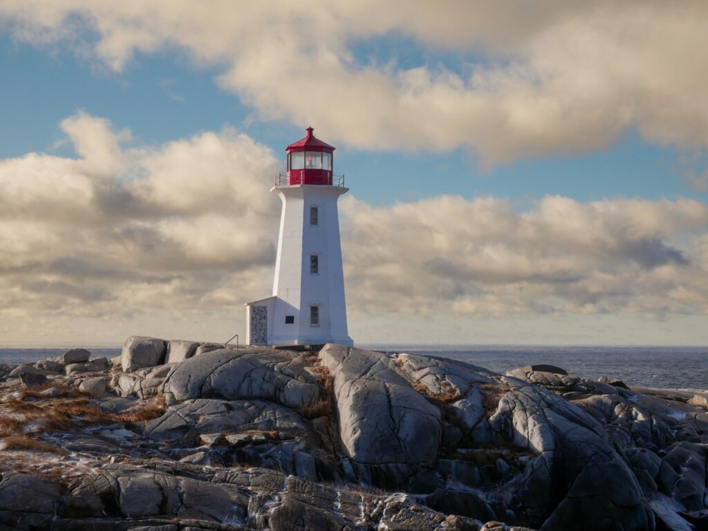 Peggy's Cove lighthouse standing tall on black rocks in Nova Scotia